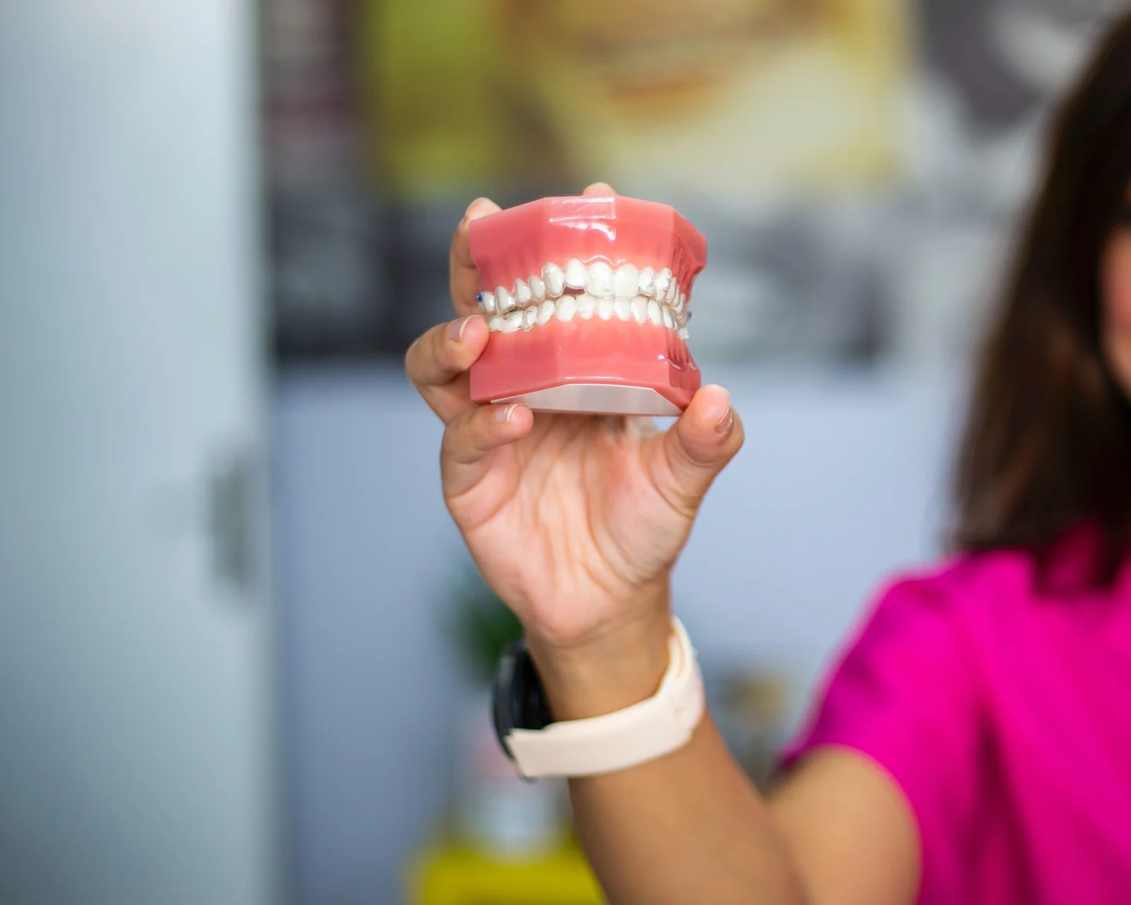 Profissional segurando modelo de arcada dentaria durante explicacao clinica