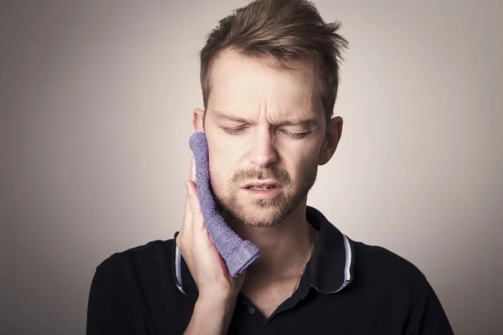 Homem aplicando compressa na mandibula ao acordar com dor