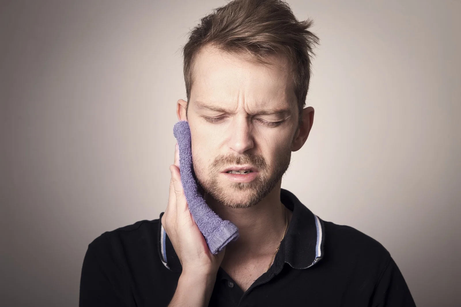Homem aplicando compressa na mandibula ao acordar com dor