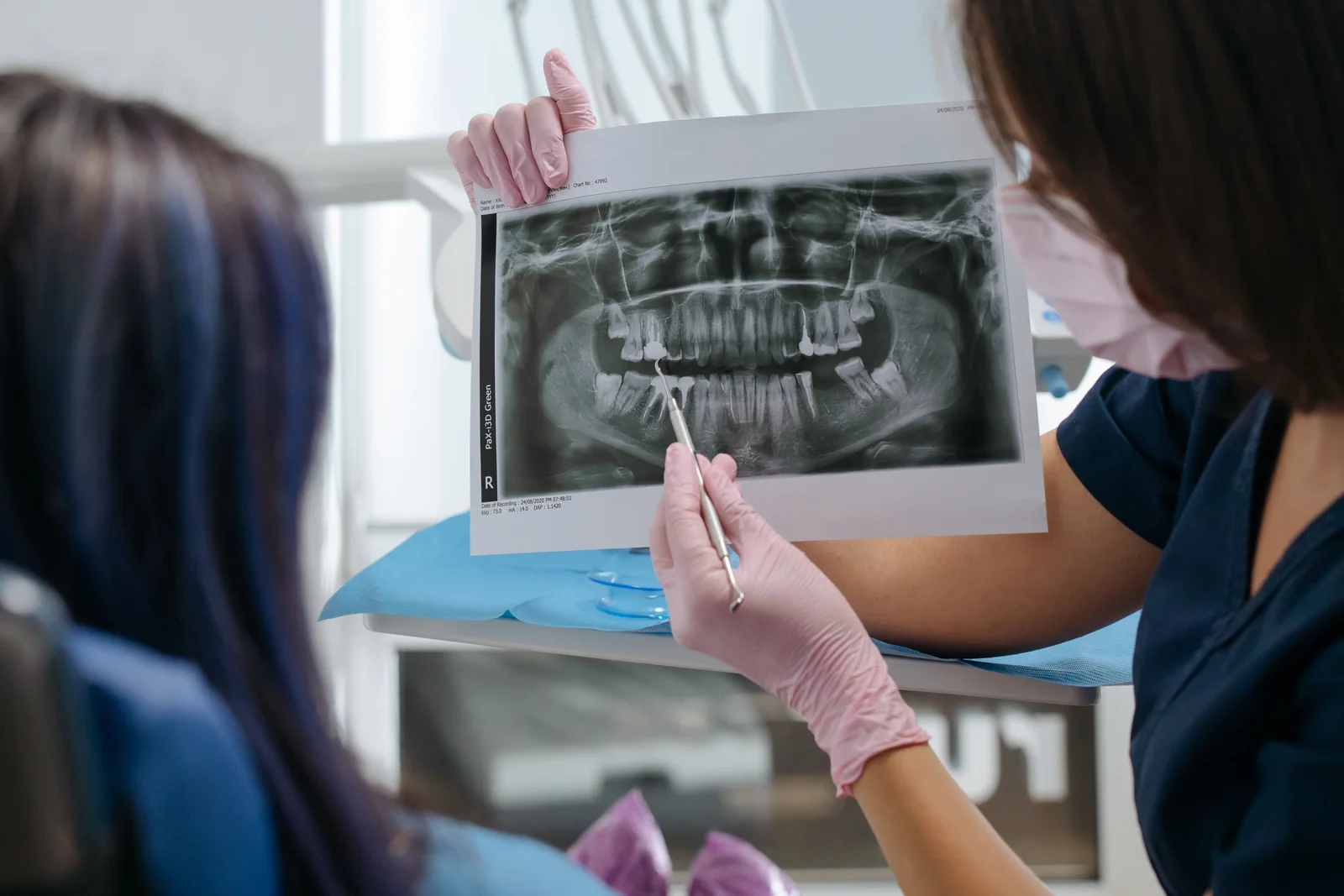 Profissional e paciente analisando radiografia odontologica em consultorio