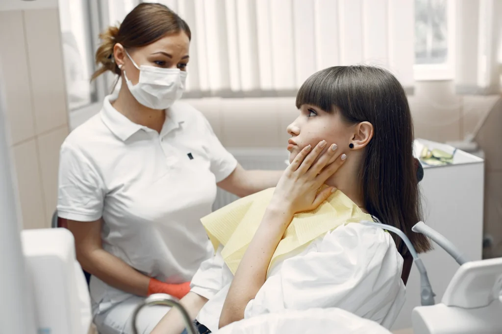 Paciente com a mao na mandibula relatando dor durante consulta odontologica