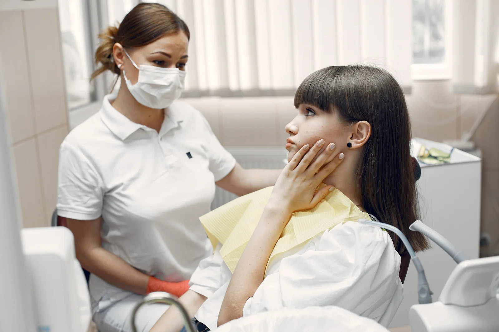 Paciente com a mao na mandibula relatando dor durante consulta odontologica